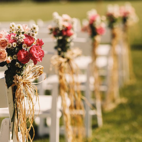 Bows of rope twine pink bouquets to white chairs