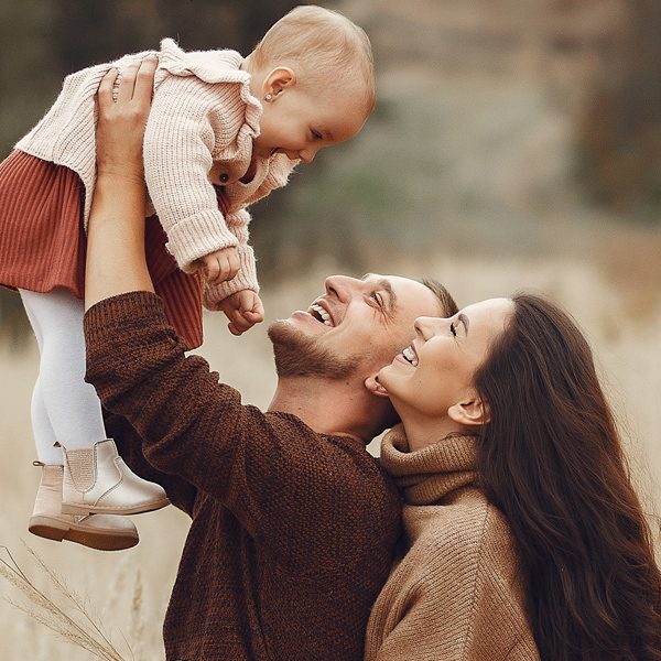 Family with cute little daughter. Father in a brown sweater. Family in a autumn field