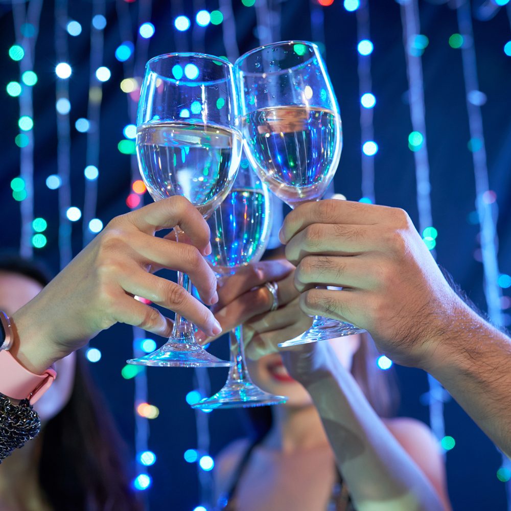 Hands of people toasting with glasses of wine in night club at party